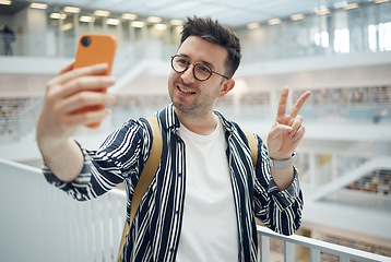 Image showing College student, man and library selfie at campus with phone, peace hand and smile on social media. Gen z, university student and smartphone app for social network, happiness and studying for success