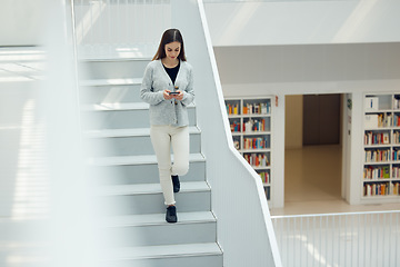 Image showing Phone, social media and research with a woman in the library walking down stairs at university or college. Books, internet and mobile with a female student on a staircase in a bookstore for education