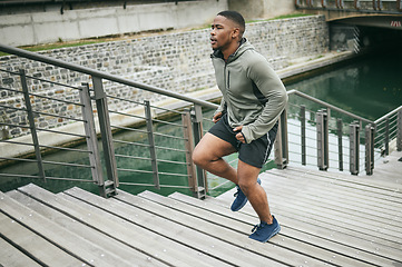 Image showing Fitness, runner or black man running on stairs for legs training, exercise or workout in city of in Miami, Florida. Steps, bridge or healthy sports athlete with wellness goals, motivation or mission