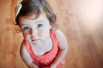 Image showing Cute, adorable and little girl standing while looking up with sweet face on wooden floor at home. Portrait of small girl child, toddler or kid in pink dress, childhood or innocent youth at the house