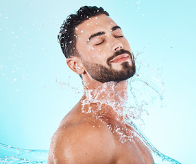 Image showing Water, splash and skincare with face of man for shower, self care and natural cosmetics. Luxury, hydration and refreshing with model for dermatology, wellness and cleaning in blue background studio