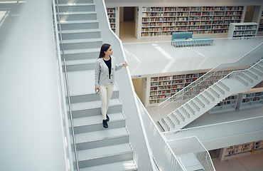 Image showing Woman, staircase and walking in the library for education, learning or knowledge from books in the mall. Female having a walk down stairs in big book shop or store for reading or development indoors