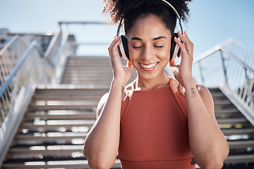 Image showing Fitness, music headphones and black woman in city streaming radio or podcast. Face, sports meditation and happy female athlete listening to song or audio outdoors by stairs after training or workout