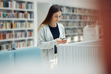 Image showing Library, phone and woman student networking on social media, mobile app or internet in college. Bookstore, knowledge and young female typing or reading a text message on her cellphone at university.