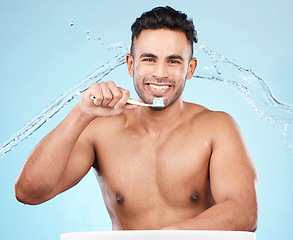 Image showing Teeth, dental care and water splash, man with toothbrush and toothpaste on blue background with smile on face. Morning routine, healthcare and fresh studio portrait of model in India brushing teeth.