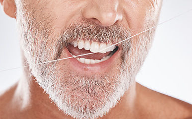 Image showing Floss, dental and face of senior man in studio isolated on a gray background. Cleaning, hygiene and elderly male model with product flossing teeth for oral wellness, tooth care and healthy mouth.