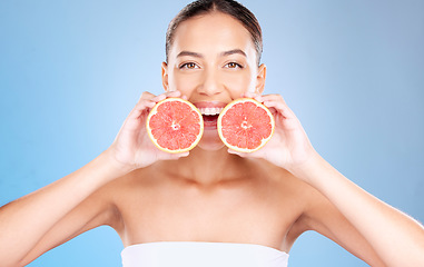 Image showing Woman, studio portrait and grapefruit for skincare, natural cosmetic or health by blue background. Model, fruit and smile for nutrition, vitamin c or self care beauty for aesthetic by studio backdrop