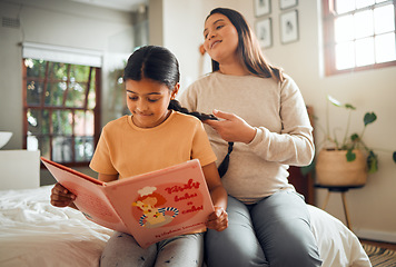 Image showing Family, book or education and a girl reading in a bedroom with her mom playing with her hair in their home. Books, learning and love with a mother and daughter bonding while sitting on a bed together