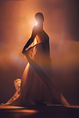 Image showing Orange lighting, fantasy and silhouette of woman with stylish dress for creative fashion, art deco and beauty. Dance, aesthetic and shadow of girl pose for dream, magic and freedom in glowing studio