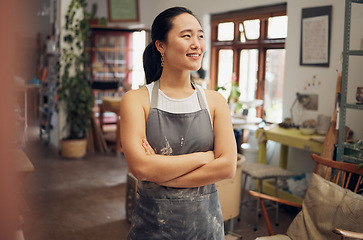 Image showing Asian woman, potter and arms crossed in pottery studio, small business or ceramic workshop with ideas, vision or goals. Smile, happy and clay product worker with confidence and creative store design