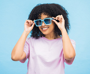 Image showing Black woman, sunglasses and smile on a blue background with happy positive attitude and casual summer style. Portrait of African American female, person or lady model smiling in happiness for fashion