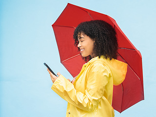 Image showing Phone, umbrella and mockup with a black woman in studio on a blue background for insurance or communication. Mobile, winter and mock up with an attractive young female typing a text message