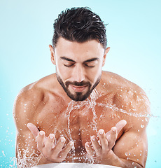 Image showing Man, water splash and face cleaning in blue background studio for grooming hygiene, skincare wellness and cosmetics dermatology care. Model hands, facial and body washing or morning beauty routine