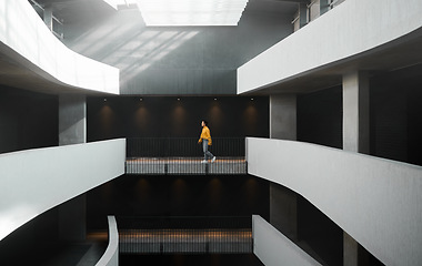 Image showing Architecture, lighting and walking woman in a building for work, entrepreneurship and start of job. Design, professional and designer on a walk in the corridor of an elegant and modern workplace