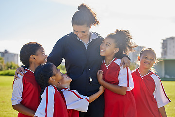 Image showing Girl football team, coach celebration and hug for success, teamwork and group diversity on grass pitch. Young female kids, soccer coaching and love for mentor woman on field for happiness in sunshine