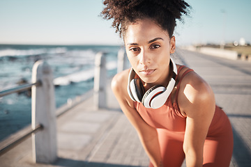 Image showing Portrait, exercise and black woman rest, beach and training outdoor, headphones and wellness. African American female tired, lady and runner with headset, exhausted and workout for cardio and seaside