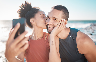 Image showing Selfie kiss, fitness and couple with a phone for streaming, training and love at the beach in Bali. Gratitude, exercise and affectionate man and woman with a smile for a mobile photo after a workout