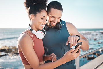 Image showing Fitness, couple and phone with smile for social media, communication or discussion relaxing by the beach. Happy man and woman smiling in happiness looking or browsing on smartphone by the ocean coast