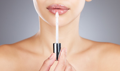Image showing Woman, lips and lip gloss application for beauty, makeup shine and skincare wellness in grey background studio. Model, lipstick tool or brush for cosmetics dermatology glow or luxury salon product