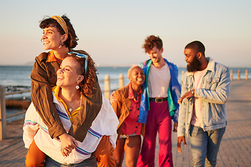 Image showing Summer, diversity and piggyback with friends on the promenade by the sea or ocean during vacation. Water, holiday and friendship with a man and woman friend group walking while bonding together