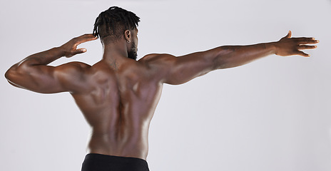 Image showing Back, body and mockup with a model black man posing in studio on a gray background for fitness or exercise. Muscle, health and wellness with a strong male athlete standing or flexing for power