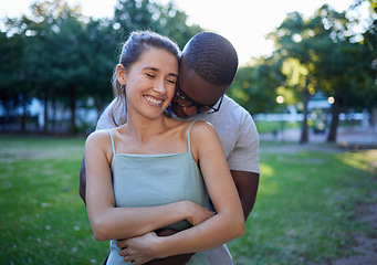 Image showing Happy interracial couple, hug and smile for romance, love or care or together in a nature park. Woman smiling with man hugging her for relationship embrace, support or trust kissing shoulder outside