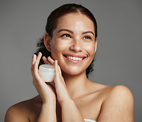 Image showing Black woman, face and skincare cream container with healthy beauty glow and natural freckles. Thinking cosmetic girl with smile and luxury facial lotion product on gray studio background.