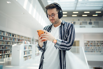 Image showing Phone music, headphones and student in library, university, or college research on mental health, wellness and education. Bookshelf, knowledge and creative, geek man listening to audio on mobile app