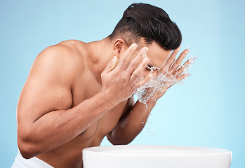 Image showing Clean, grooming and man washing face with water for skincare, morning hygiene and care of body on a blue studio background. Beauty, wellness and model with a facial water splash for cleaning