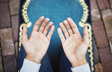 Image showing Hands, muslim and praying in worship to Allah, god or creator on salah mat making dua on the floor. Hand of islamic man in pray for islam religion, spiritual or respect for belief or culture outside