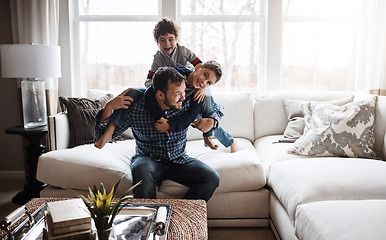 Image showing Goofy, funny and bonding father with children on the sofa for playing, quality time and crazy fun. Love, happy and boy kids piling onto dad with energy on the couch of their family home together