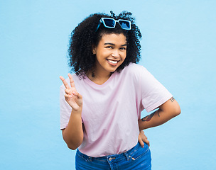 Image showing Black woman, peace sign and portrait of a model isolated with blue background in a studio. Young, happy smile and v hand gesture of a person feeling relax with happiness alone with casual style