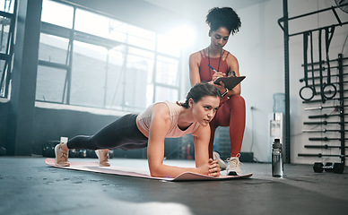Image showing Personal trainer, fitness and clipboard with a black woman coaching a client in a gym during her workout. Health, exercise or training and a female athlete doing a plank with her coach writing notes