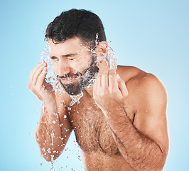 Image showing Man, water splash face and cleaning in studio for wellness, health and self care groom by blue background. Model, bathroom and water with hands for healthy facial, self love and cosmetics by backdrop
