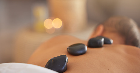 Image showing Spa, man and stone massage to relax, luxury and health for body care, peace and holistic care. Male, gentleman and lying on table at resort, rocks and wellness therapy for skincare and stress relief.