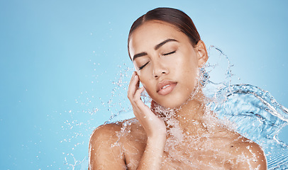 Image showing Woman, hand and water splash for face skincare, dermatology wellness or Brazilian healthcare grooming on blue background studio. Beauty model, water drop or facial cleaning in wet hygiene maintenance