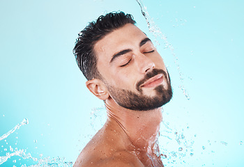 Image showing Water, splash and skincare with face of man for shower, self care and natural cosmetics. Luxury, hydration and refreshing with model for dermatology, wellness and cleaning on blue background studio