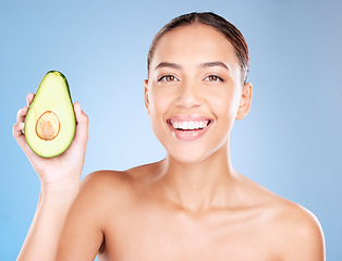 Image showing Woman, studio portrait and avocado skincare with smile, health or wellness by blue background. Model, fruit and face with natural cosmetic beauty, glow or healthy aesthetic with self care by backdrop