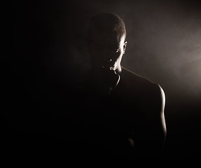 Image showing A handsome, muscular young african american man in studio against a dark background. A macho male athlete looking thoughtful isolated on black. Exercising body and mind. A question of mental health