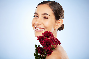 Image showing Skincare, flowers and beauty portrait of woman on studio blue background for healthy skincare, wellness and luxury makeup in Spain. Face, smile and model with floral chrysanthemum for natural perfume