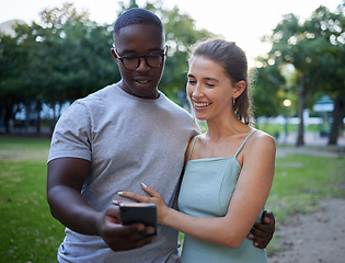 Image showing Love, phone or couple of friends in a park on social media or relaxing on a romantic date in nature at sunset. Interracial, black man and happy woman enjoying online content on a fun holiday vacation