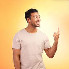 Image showing Mockup, pointing up and man advertising in studio isolated on a yellow background. Thinking, branding and happy male model showing copy space for product placement, mock up or marketing promotion.