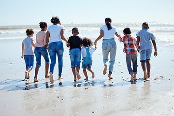 Image showing Big family, beach walk and water for vacation, sunshine and bonding with interracial diversity by waves. Happy family, mother and holding hands for solidarity, care and love on holiday by sea