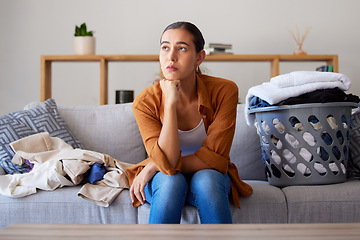 Image showing Laundry, bored and break with a woman cleaner sitting on a sofa in her living room at home for spring cleaning. Depression, cleaning and laundry basket with a female housekeeper resting on a couch