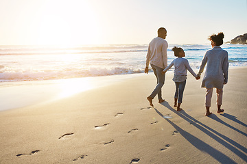 Image showing Black family, sunset and beach walk during summer on vacation relaxing at a peaceful scenery by the ocean. Sea, footprints and parents with daughter, child or kid with childhood freedom