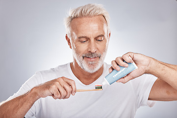 Image showing Face, toothpaste and senior man with toothbrush in studio isolated on a gray background. Hygiene, cleaning and elderly male model holding product for brushing teeth, dental wellness and healthy gums.