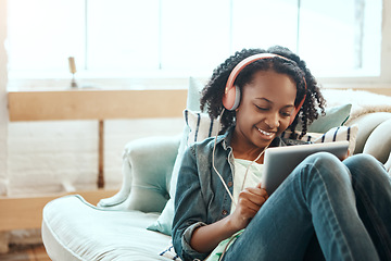 Image showing Tablet, headphones and black girl on the sofa to relax while listening to music, radio or podcast. Rest, technology and African child watching a video on mobile device in her living room at home.