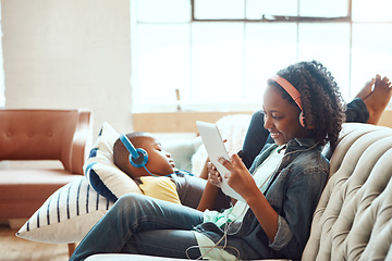 Image showing Siblings, tablet and headphones for relax on sofa in the living room enjoying entertainment or wifi at home. Happy sister and brother relaxing on couch listening to music or online streaming indoors