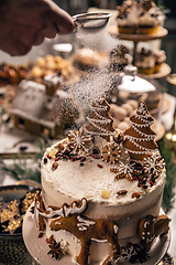 Image showing Woman powdering gingerbread cake