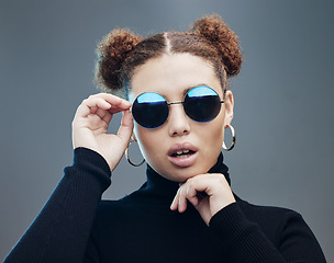 Image showing Face, sunglasses and fashion with young woman, style and designer with trendy brand and gen z against studio background. Style, edgy and young girl, marketing with fashion model and stylish beauty